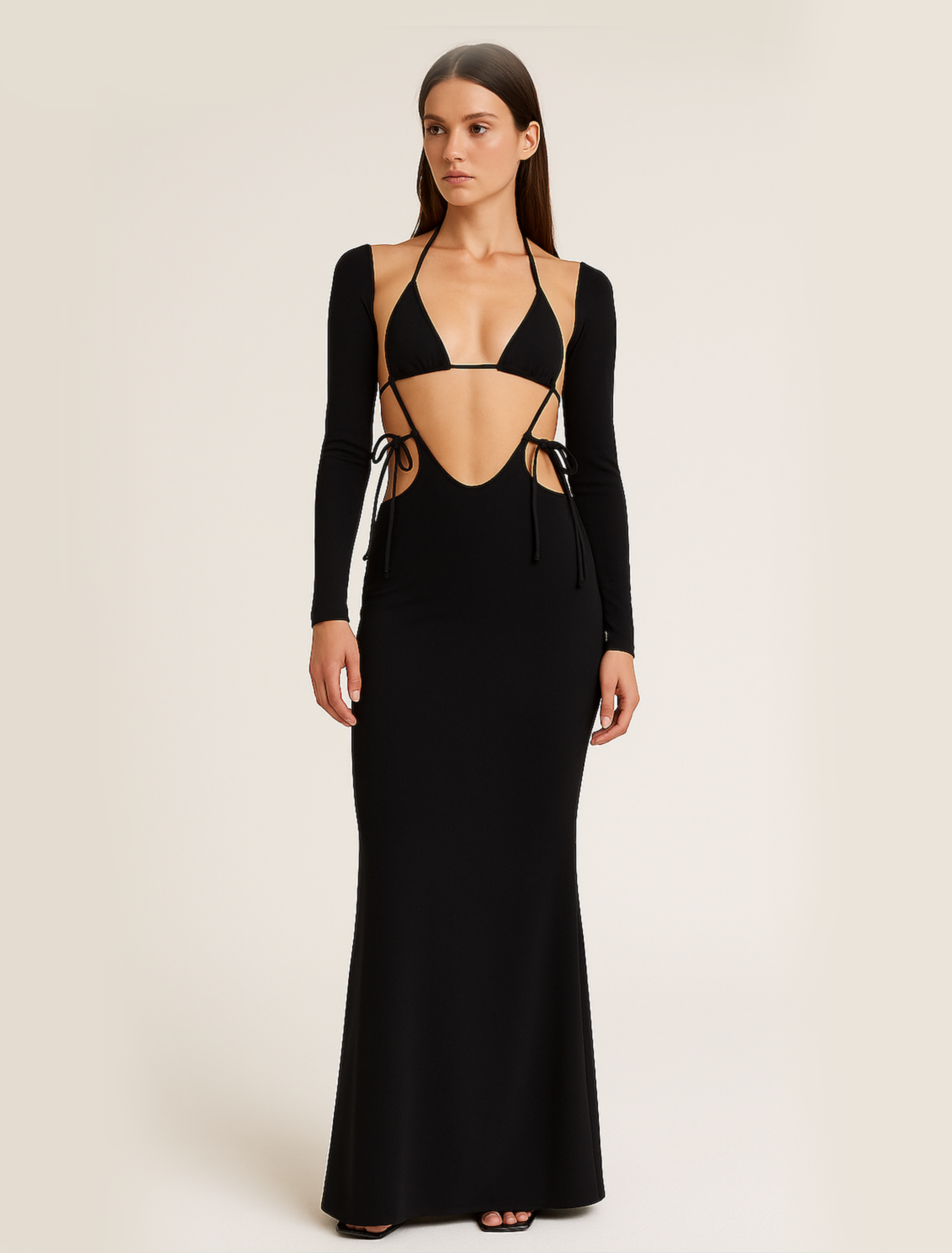 Woman wearing a black long-sleeve evening gown with cut-out design on a beige background