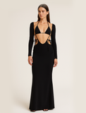 Woman wearing a black long-sleeve evening gown with cut-out design on a beige background